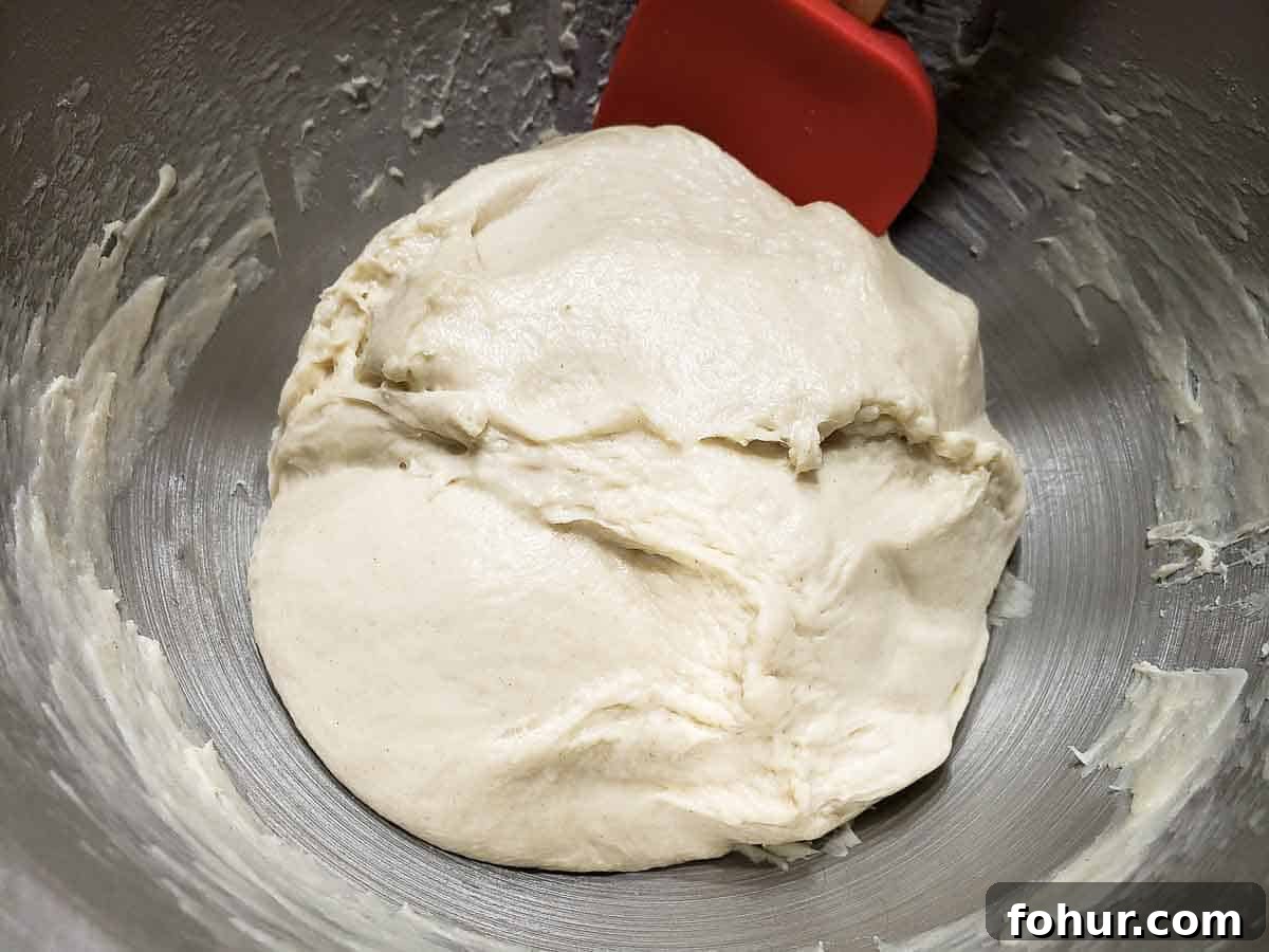 Cinnamon Swirl Raisin Bread Recipe: Homemade Loaf 4 soft dough in a silver bowl with a red spatula.