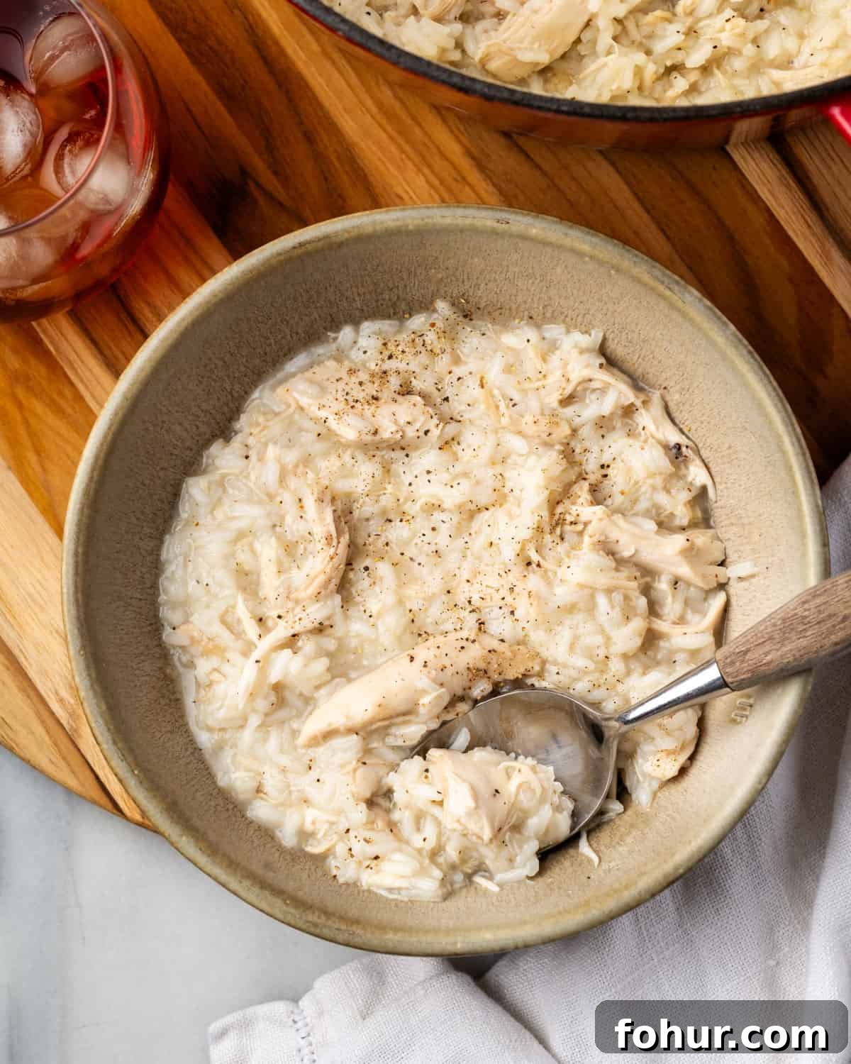 A bowl of southern-style chicken and rice topped with black pepper sitting on a wooden tray.