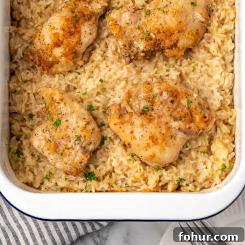 A pan of baked chicken and rice casserole sitting on a marble counter.