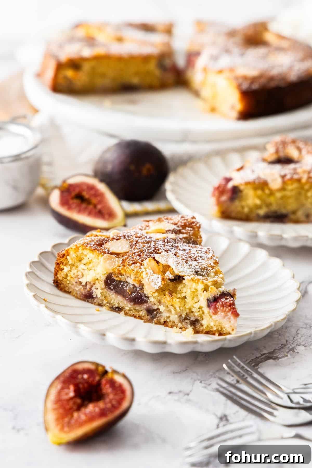 Gluten-Free Fig Cake, with two slices cut on small white plates, with some fig slices around the edge.