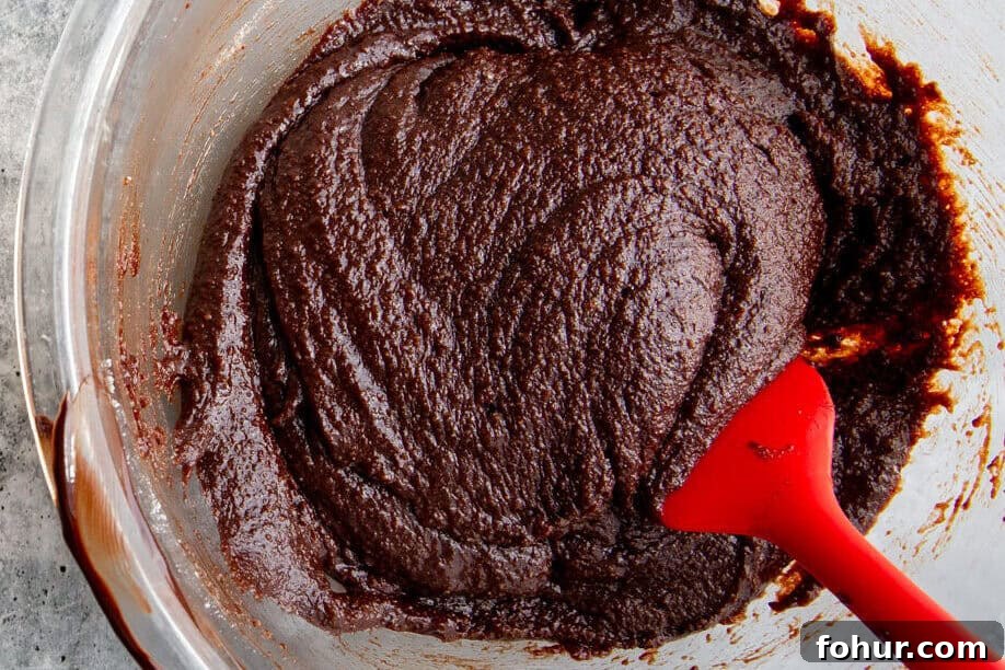 Fudgy Pumpkin Cheesecake Swirl Brownies Recipe 4 brownie batter mixed in a glass bowl with a red spatula