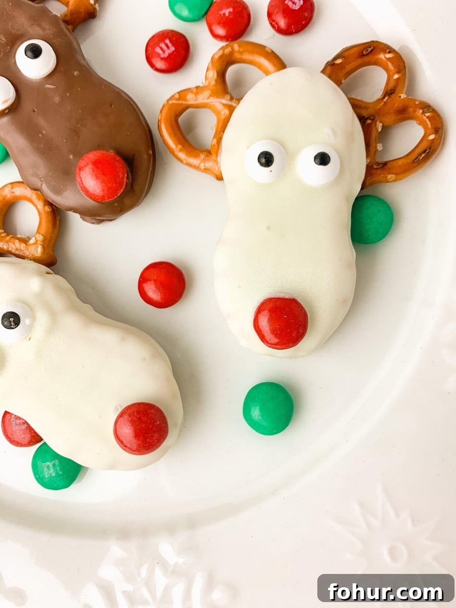 White Chocolate Candy Covered Peanut Butter Reindeer Nutter Butter Cookies, with red and green M&Ms sprinkled around on a plate.