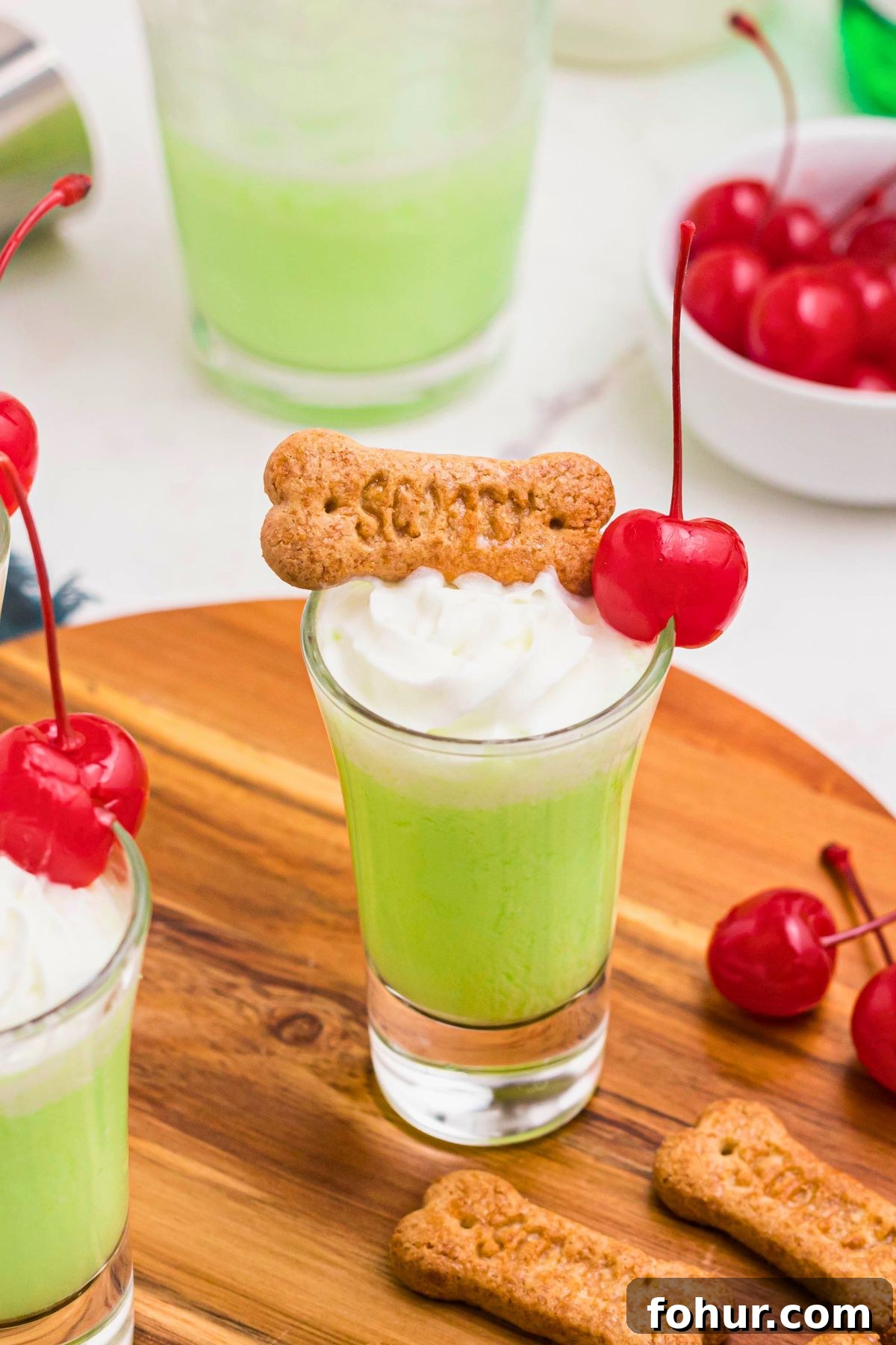 Scooby Snack Shot Cocktail Recipe 2 Green shot in a shot glass topped with a cherry and whipping cream.