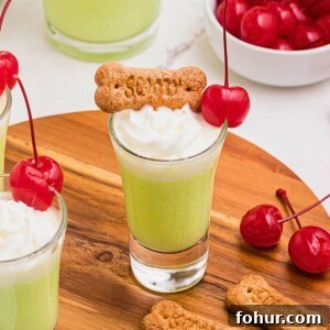 Scooby Snack Shot Cocktail Recipe 12 Green liquid in a shot glass, topped with graham cracker snack and bright red cherry.