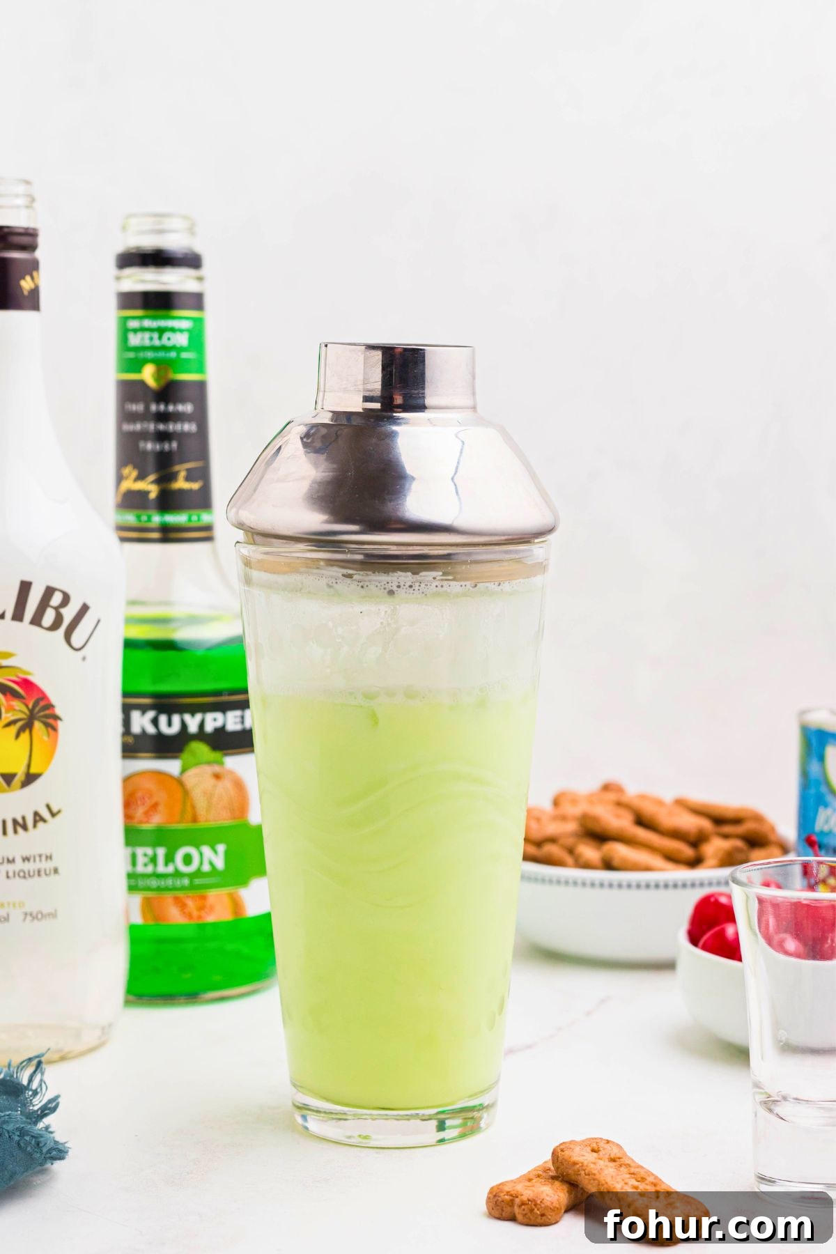 Scooby Snack Shot Cocktail Recipe 5 Green scooby snack shot mixture in a clear cocktail shaker on a white marble board.