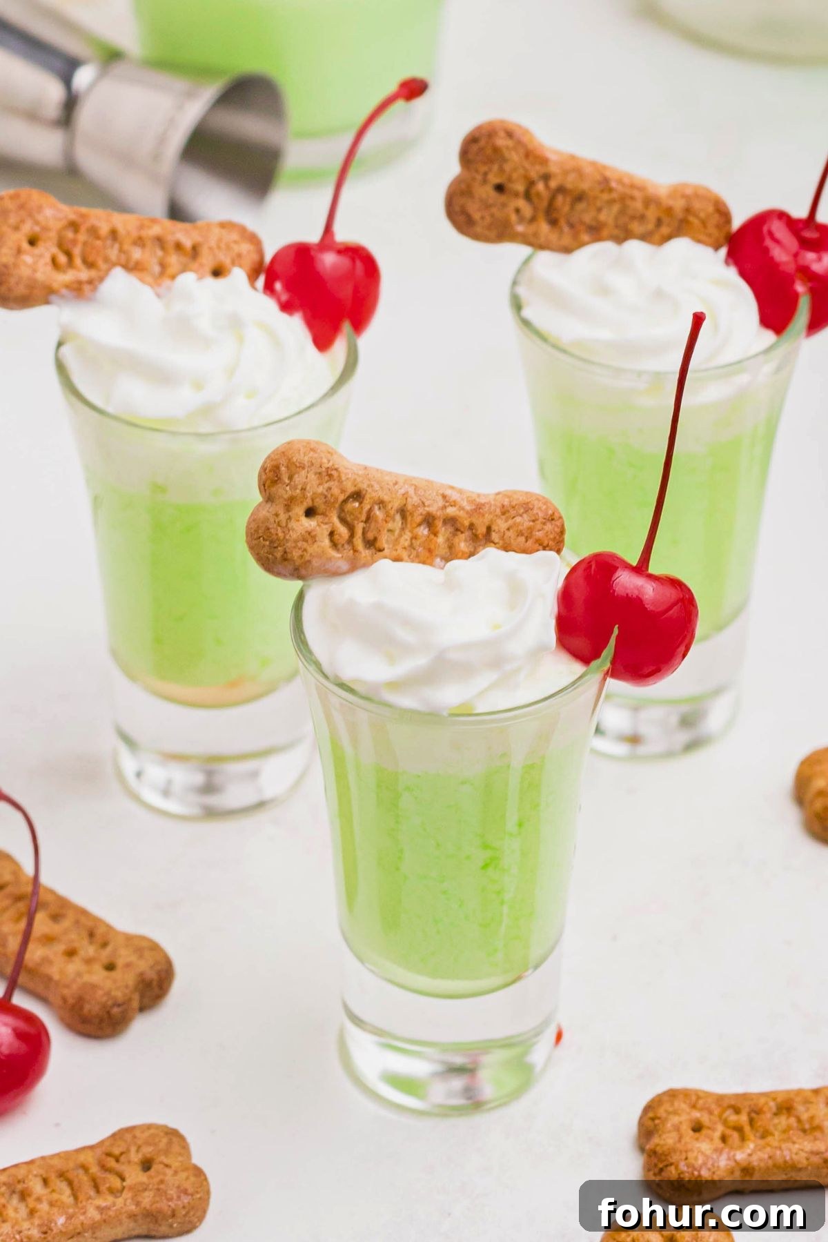 Scooby Snack Shot Cocktail Recipe 7 Green scooby snack shot in a small glass, topped with whipping cream and a cherry.