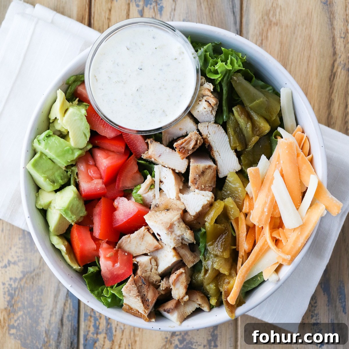 Southwest Grilled Chicken Salad with Green Chiles 5 prepared salad in a bowl with grilled chicken, avocado, tomato, hatch green chiles, shredded cheese and a side of spicy ranch