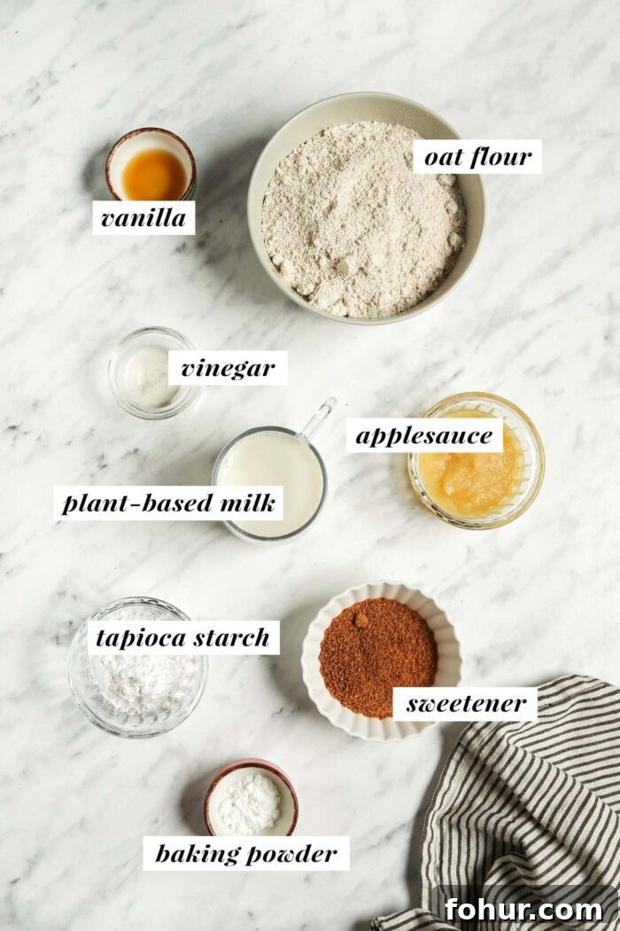Fluffy Vegan Oat Flour Pancakes (Banana-Free) 2 Oat flour, tapioca starch, sugar, vanilla and baking powder in small bowls on a marble surface. Each ingredient is labelled with text.