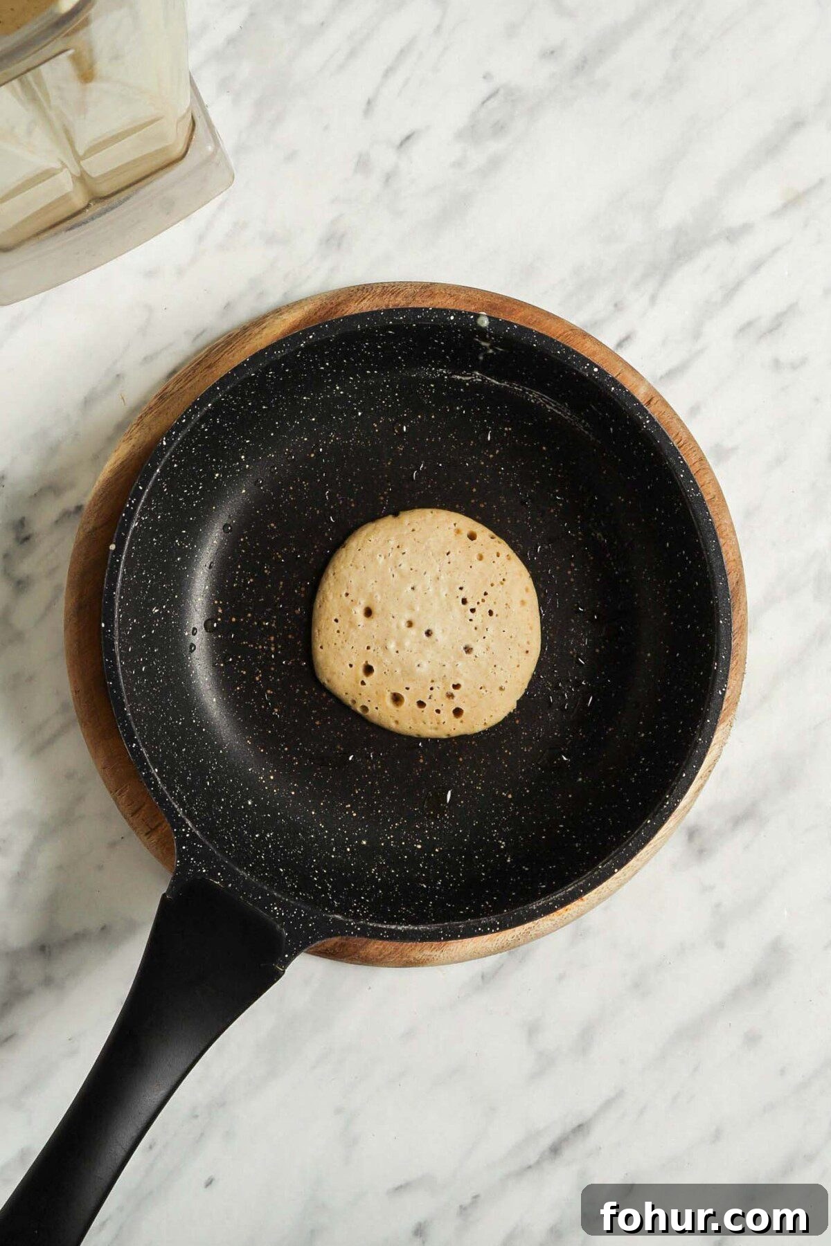 Fluffy Vegan Oat Flour Pancakes (Banana-Free) 4 A vegan and gluten-free oat banana pancake cooking in a small nonstick pan.
