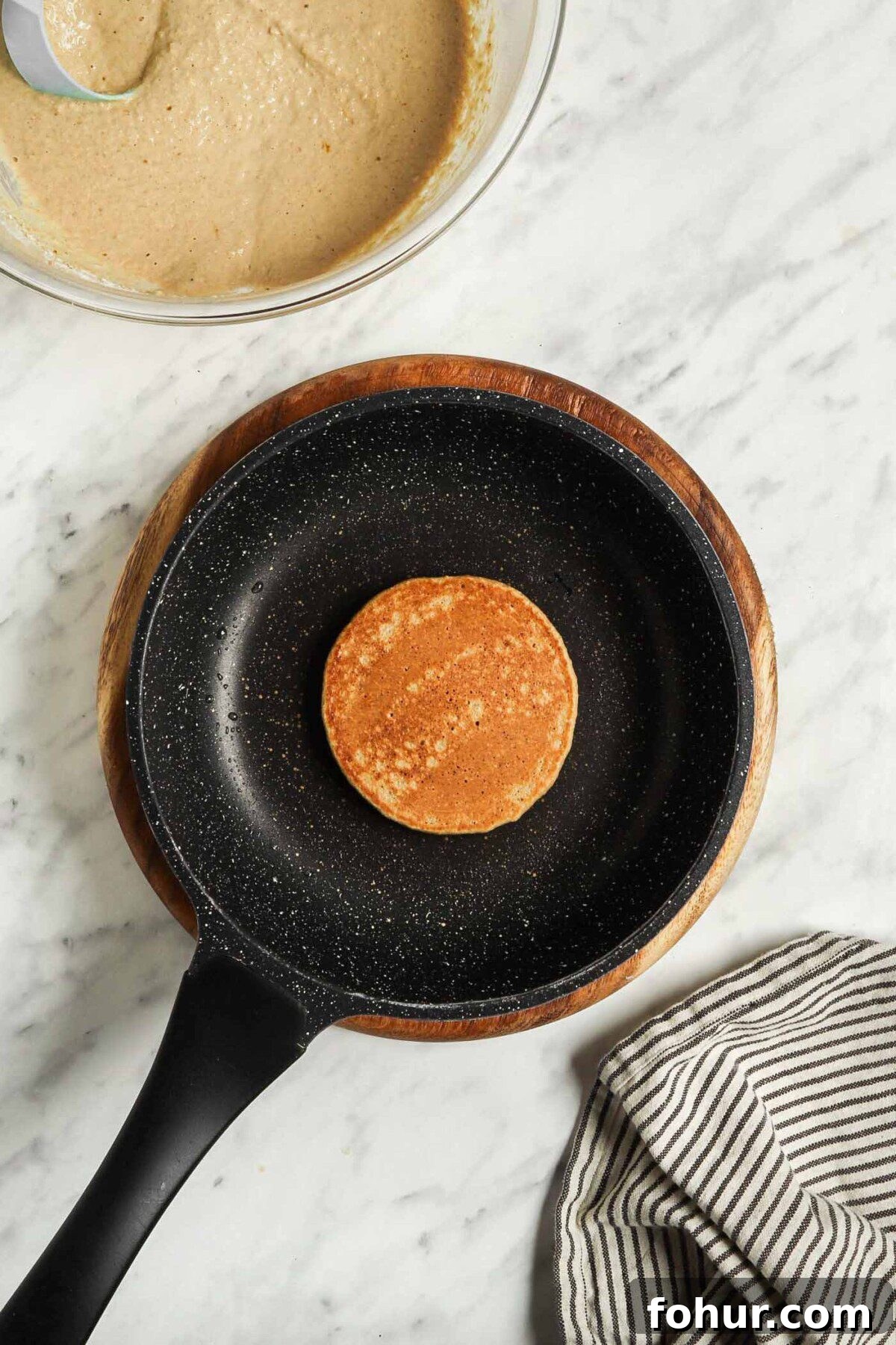 Fluffy Vegan Oat Flour Pancakes (Banana-Free) 5 A cooked, small brown pancake in a small skillet.