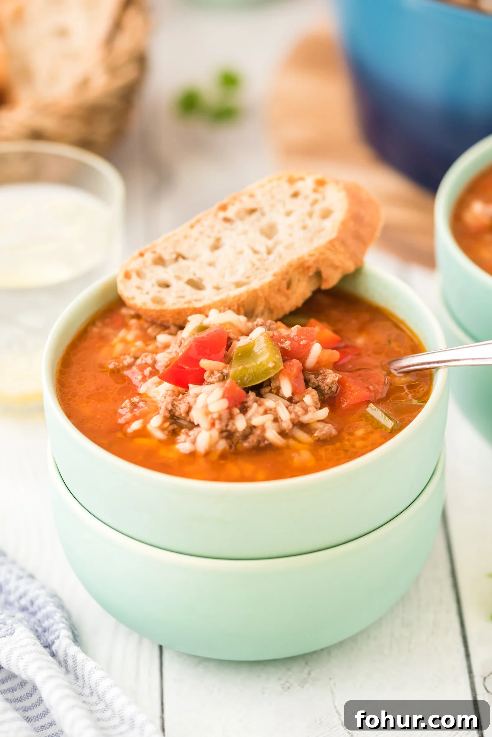 Stuffed Pepper Soup Recipe That Warms the Soul 9 a mint green bowl of soup with a chunk of crusty bread on the rim of the bowl