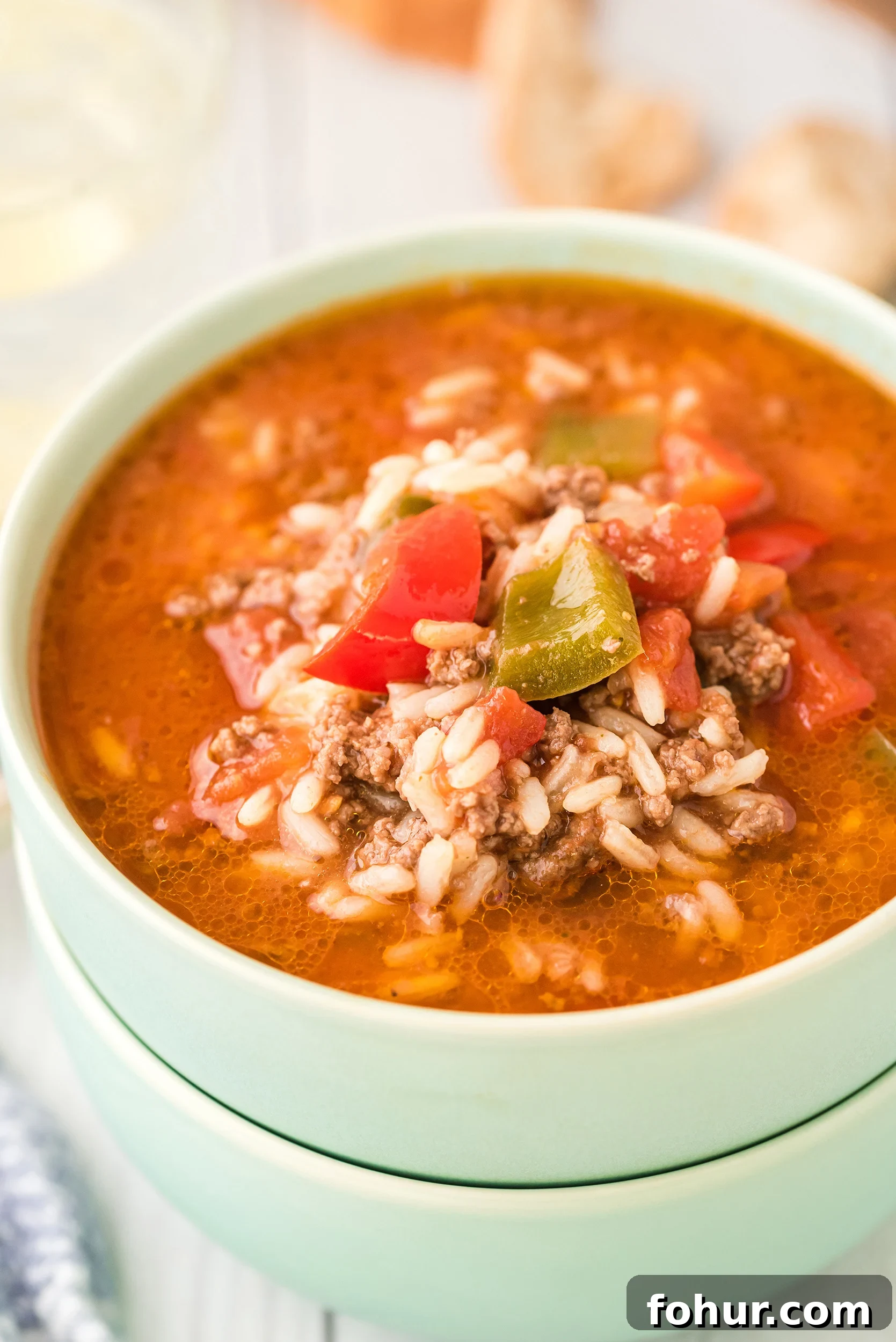 two stacked mint green bowls bowls filled with stuffed pepper soup