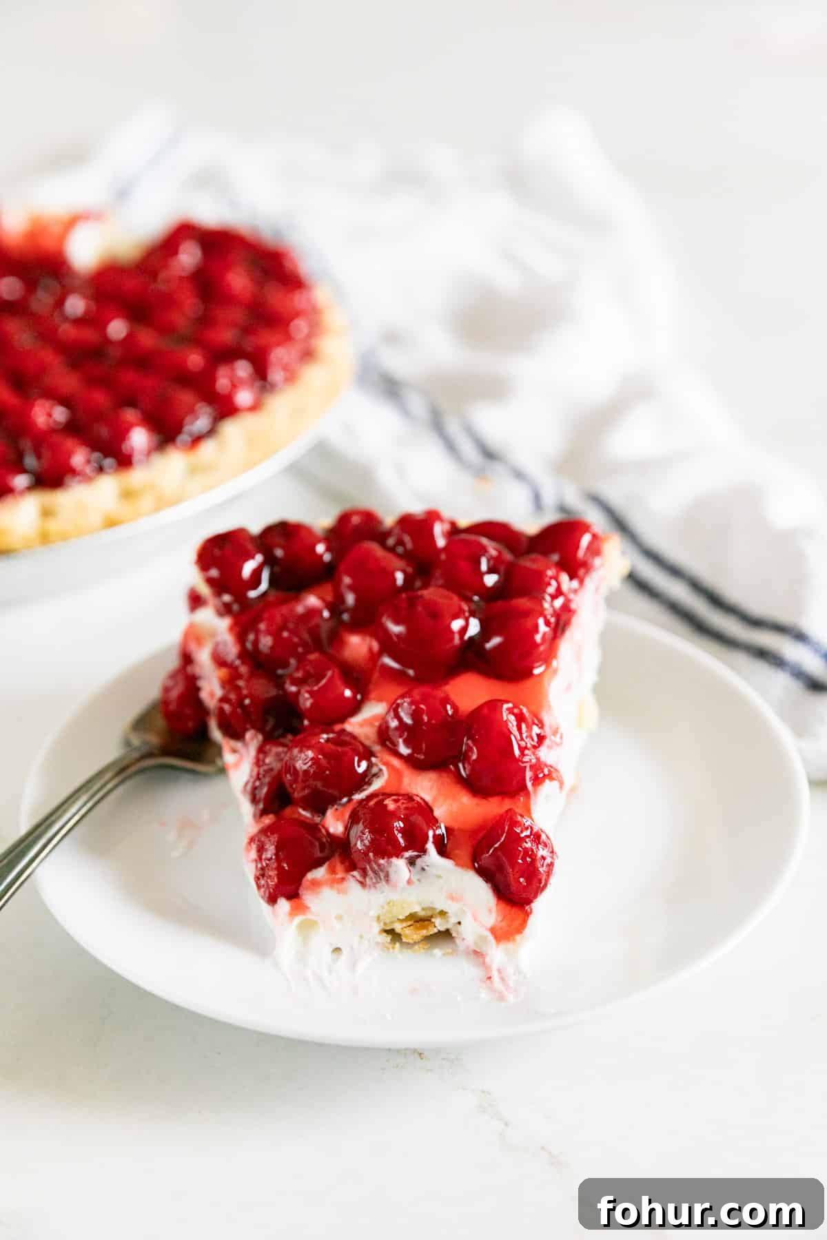 Cherry Cream Cheese Pie Recipe 12 A slice of cream cheese pie with cherries with a bite taken out of it.