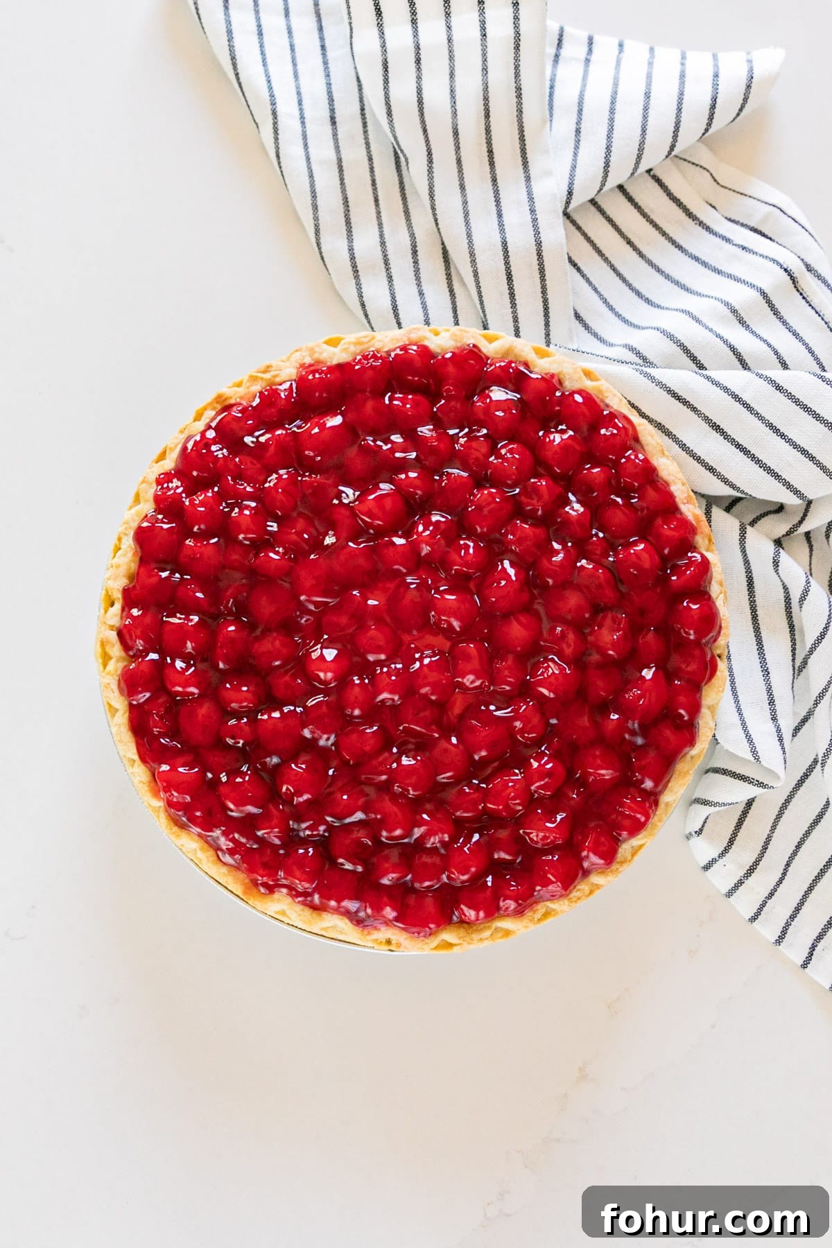 Cherry Cream Cheese Pie Recipe 3 An overhead image of cherry cheese pie with a striped napkin next to it.