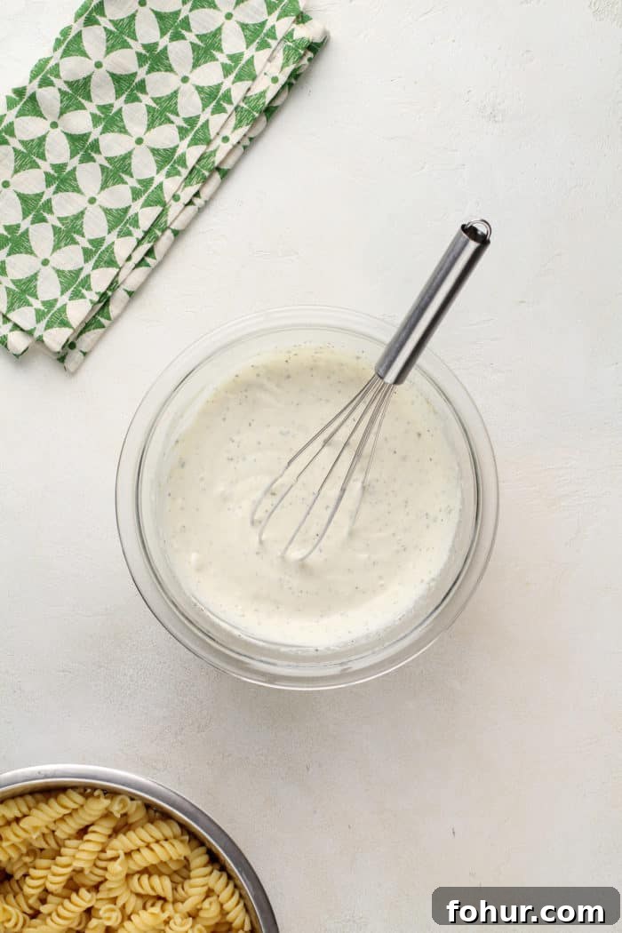 Creamy Bacon Ranch Pasta Salad with Peas and Cheddar 7 Ranch dressing for pasta salad being whisked together in a glass mixing bowl.
