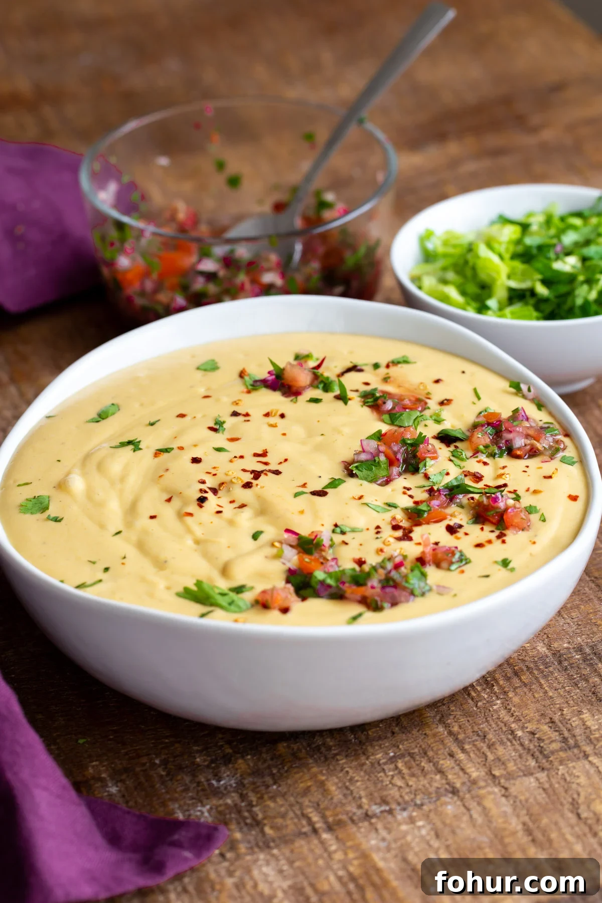 Instant Pot Vegan Cheese Sauce with Potatoes and Carrots 2 a bowl of vegan cheese sauce topped with pico de gallo and chopped cilantro
