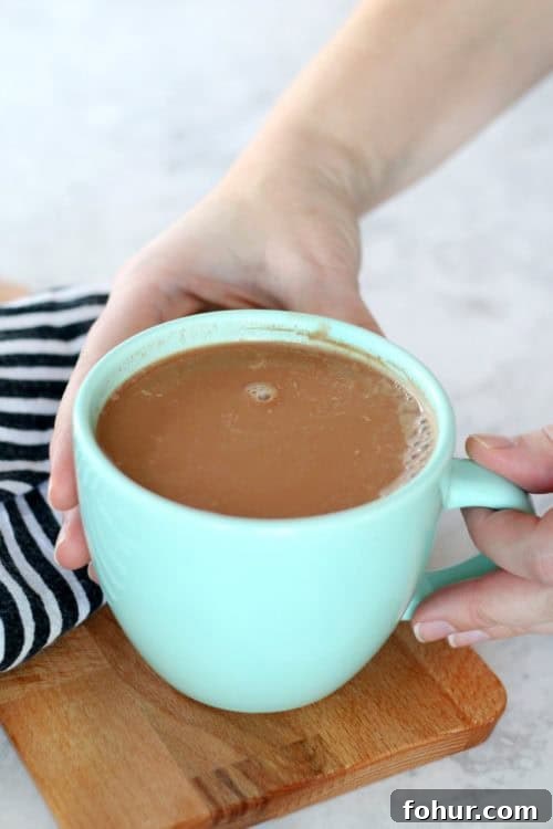 How to Make 108-Calorie Hot Cocoa (Video) 4 hands holding teal mug of cocoa