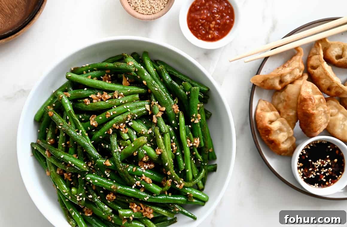 Stir-Fried Chinese Garlic Green Beans 6 Garlic Chinese Green Beans in a white bowl next to a plate with fried dumplings