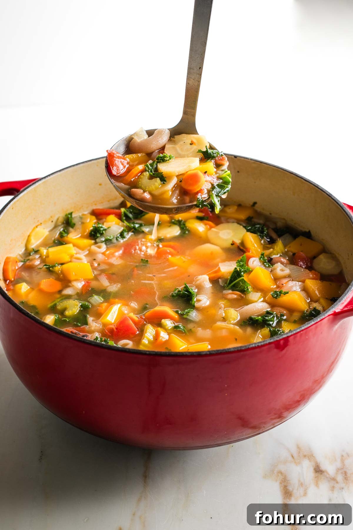 Vegan Fall Minestrone Soup with Roasted Autumn Vegetables 12 Ladling chunky minestrone soup from a dutch oven.