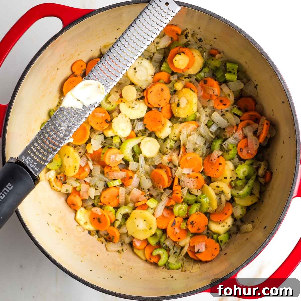 Vegan Fall Minestrone Soup with Roasted Autumn Vegetables 7 Grating garlic over a dutch oven with sauteed veggies.