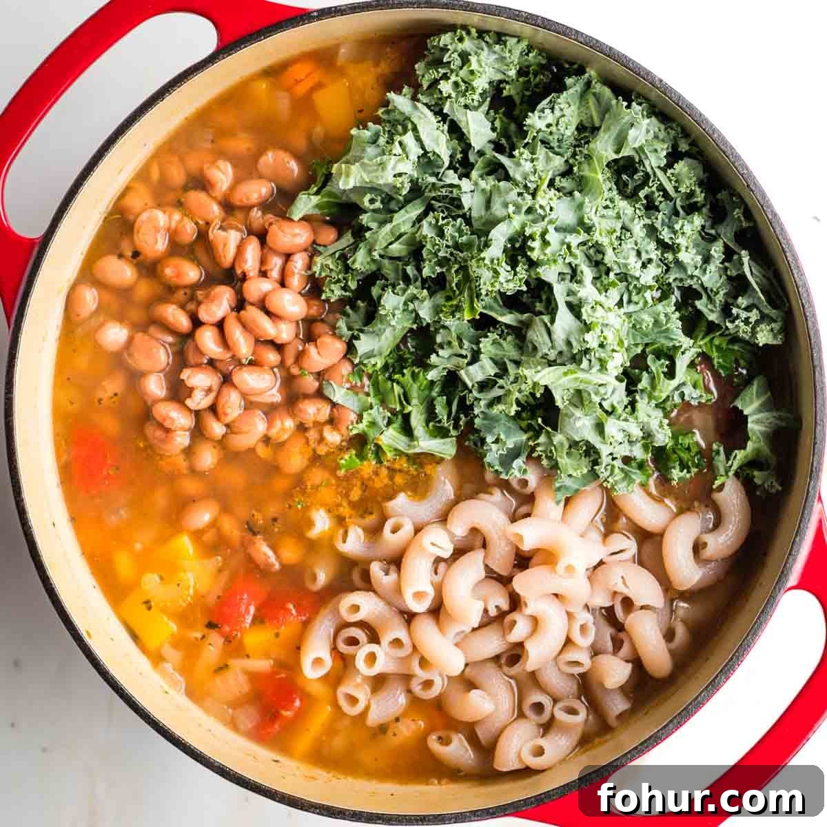 Vegan Fall Minestrone Soup with Roasted Autumn Vegetables 10 Chopped kale, pinto beans and cooked pasta in a pot of veggie soup.