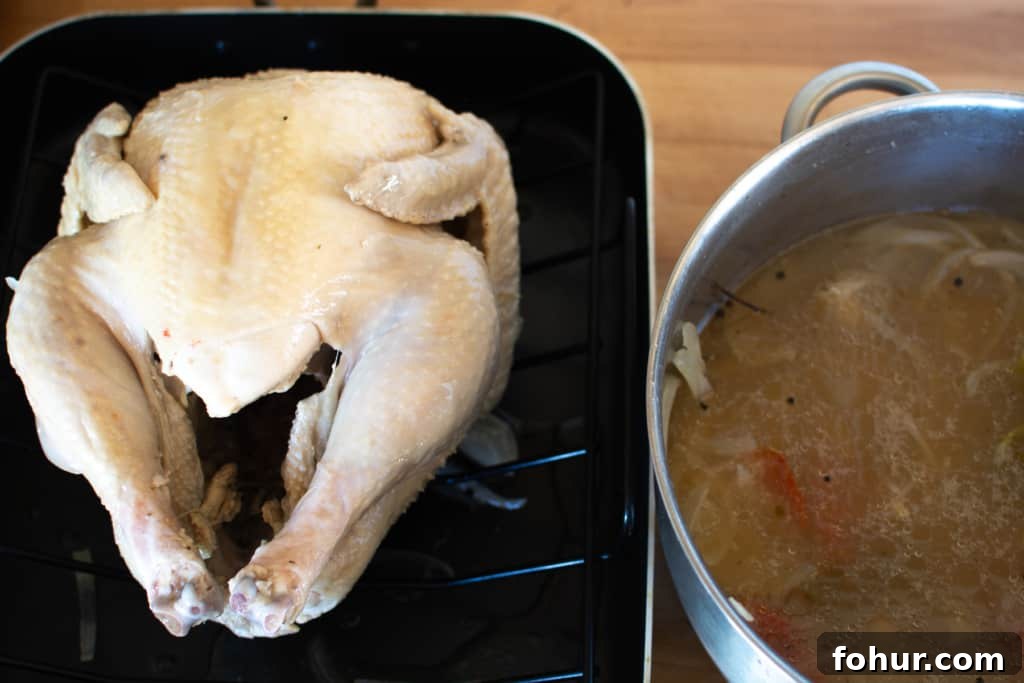 Turkey on a roasting rack next to the pot of poaching liquid
