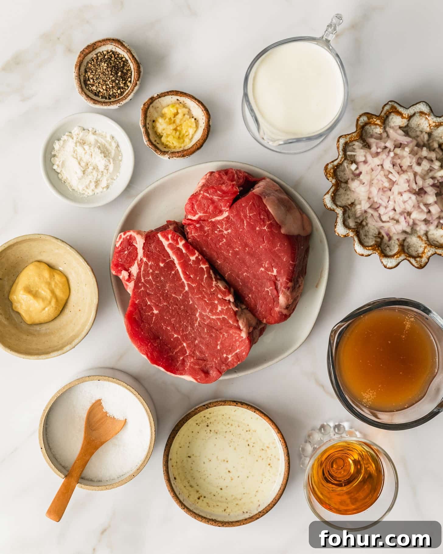 Reverse-Sear Filet Mignon Recipe with Creamy Peppercorn Sauce 2 White and brown plates of steak, shallots, cream, garlic, pepper, flour, mustard, salt, oil, brandy, and beef broth on a beige marble counter.