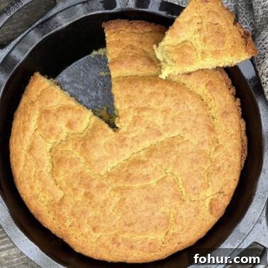 Creamy Southern Broccoli Casserole Recipe 12 A cast iron pie pan with baked golden brown southern cornbread in it with a slice on top.