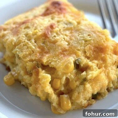 Creamy Southern Broccoli Casserole Recipe 13 A slice of corn pudding with cheese and jalapeños on a white plate.