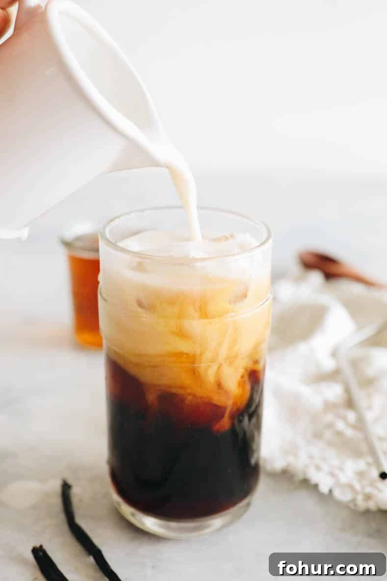 vanilla sweet foam being poured into a cup of cold brew