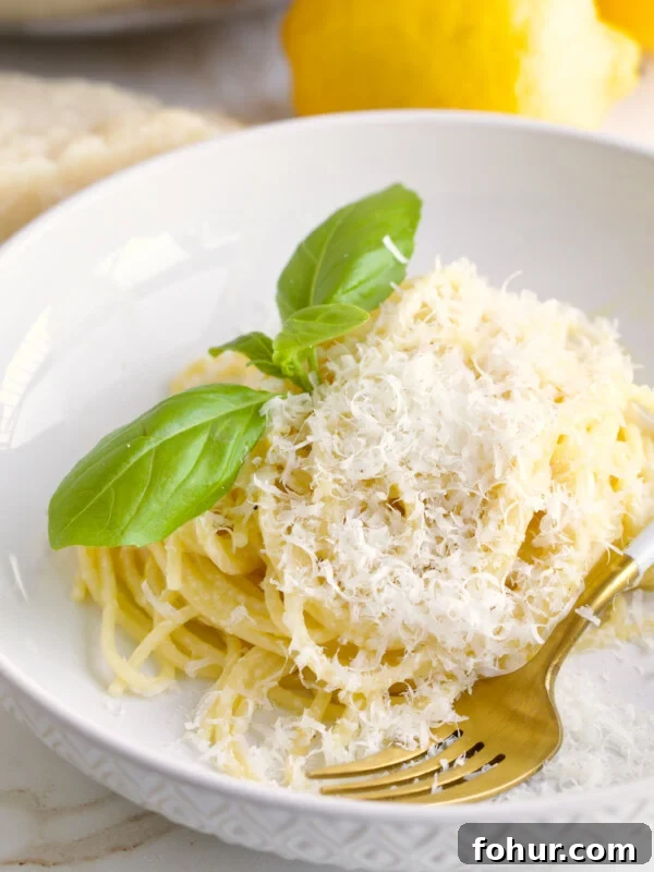 Oven Baked Italian Sausage Recipe with Peppers and Onions 11 Fork on a plate of lemon pasta recipe topped with basil.