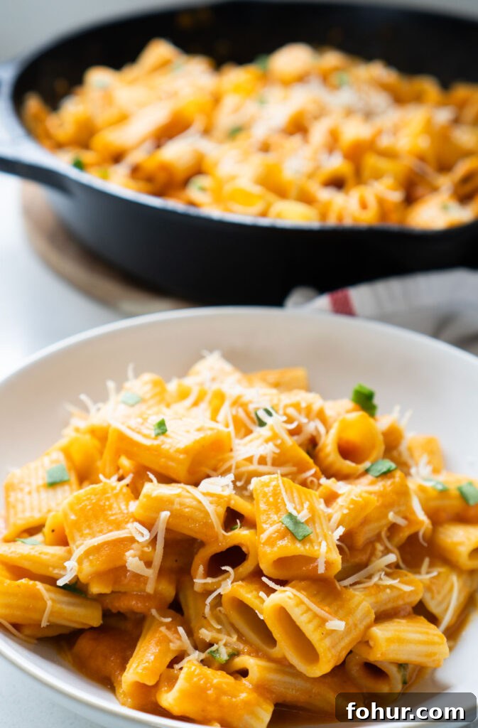 Creamy Pumpkin Pasta with Sage and Parmesan 2 creamy pumpkin pasta in white bowl in front of skillet of pasta
