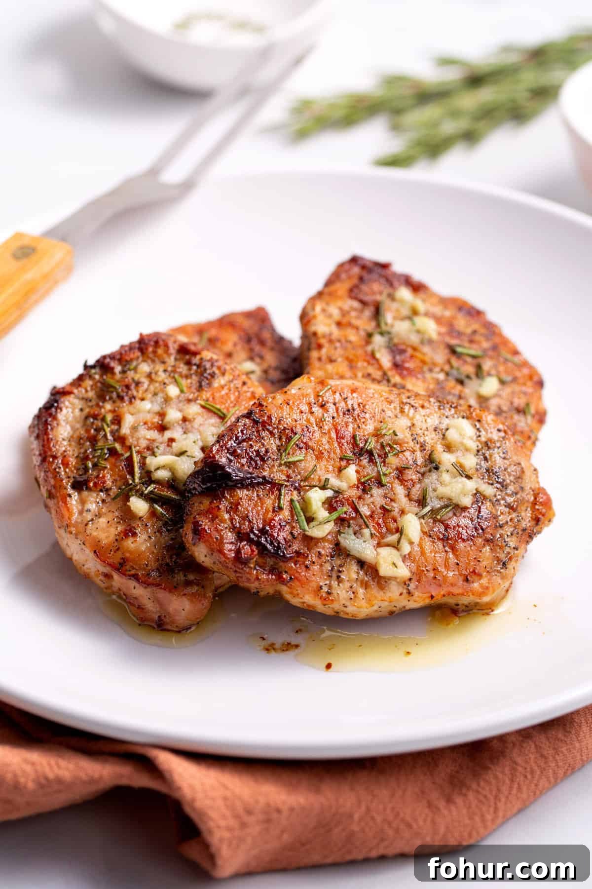 three baked pork chops served on a white round plate
