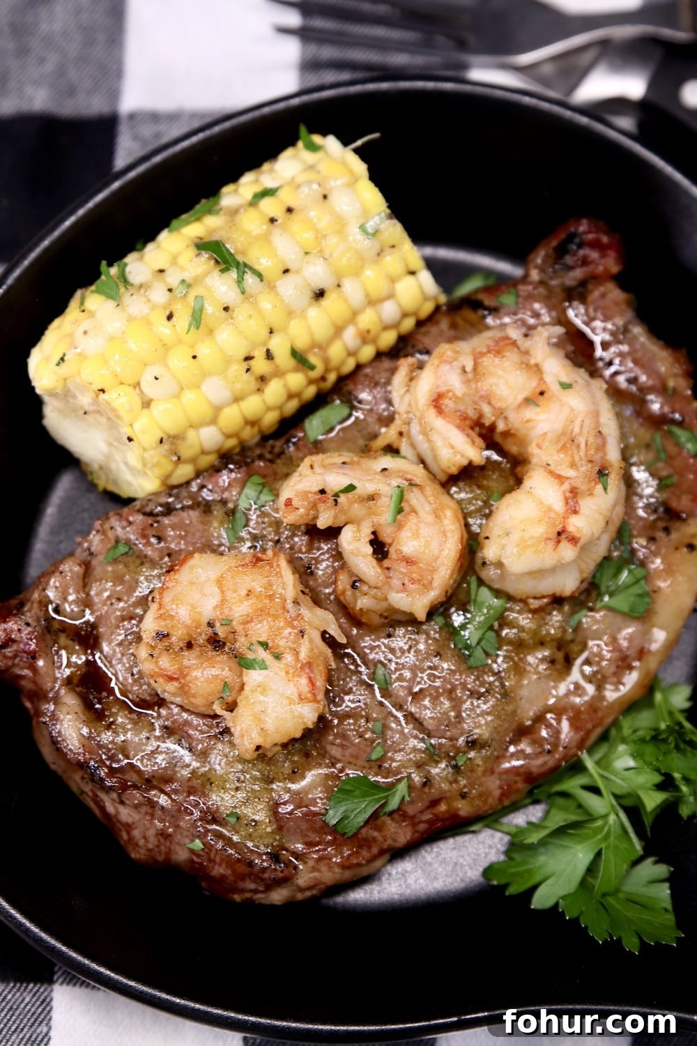 serving skillet with grilled steak, 3 shrimp, corn on the cob