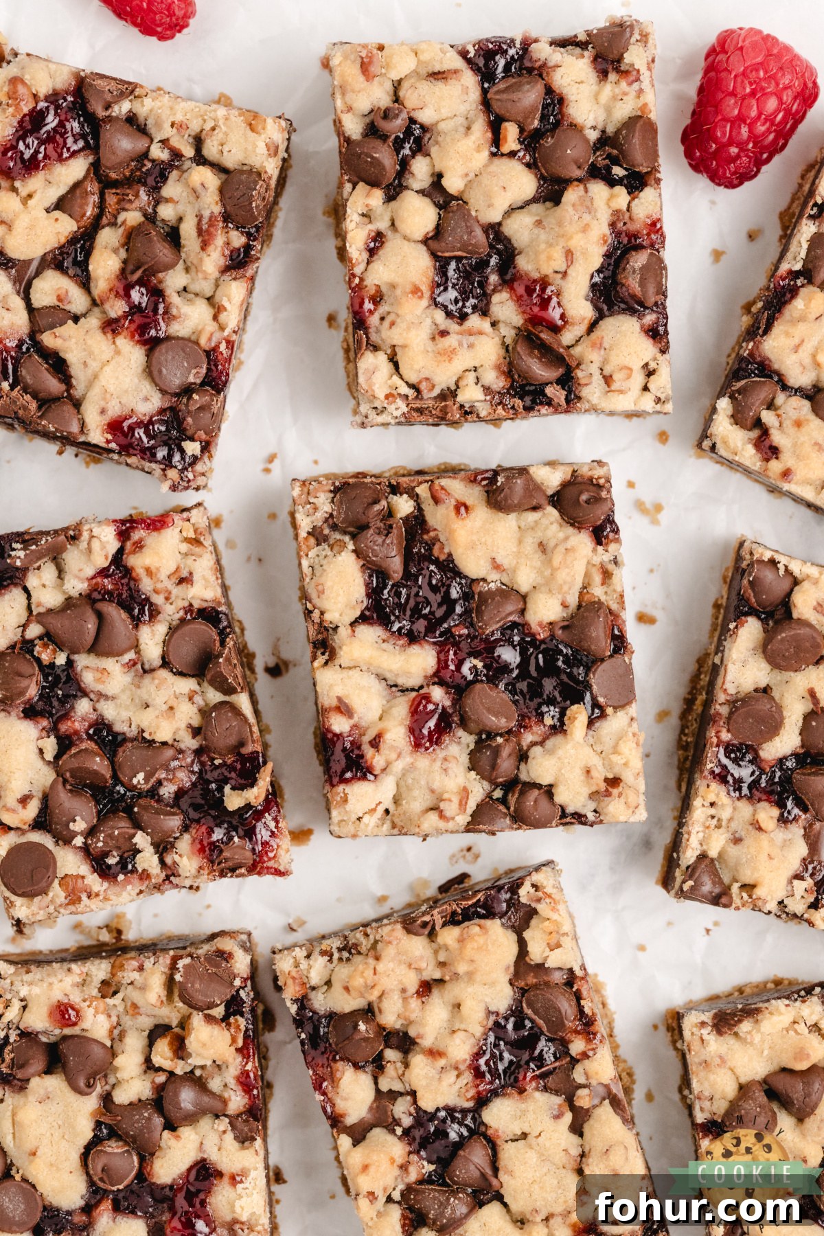 Decadent Chocolate Raspberry Shortbread Cookie Bars Recipe 5 Squares of chocolate raspberry shortbread bars arranged on parchment paper.