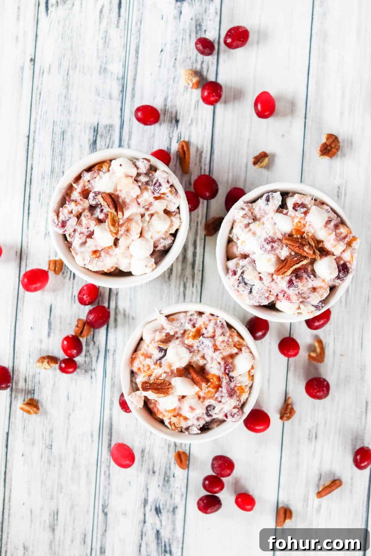 Three bowls of Cranberry Ambrosia Salad on a white board