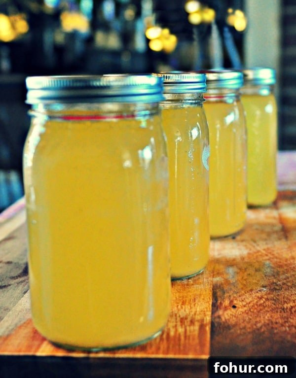 How to Make Homemade Chicken Stock from Scratch 2 4 jars of canned chicken stock on a wood table