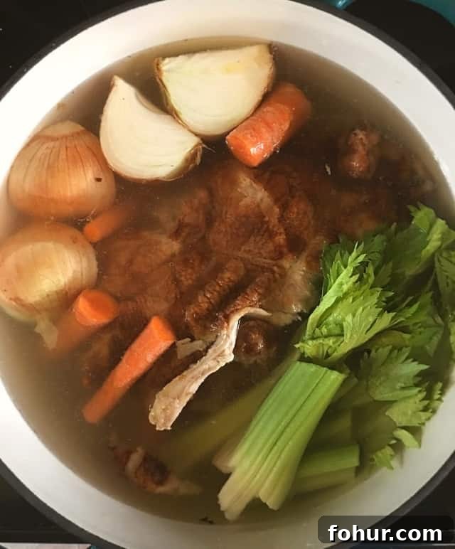 How to Make Homemade Chicken Stock from Scratch 5 a stockpot full of onion, carrots, celery