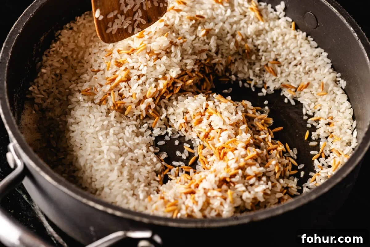Savory Garlic Rice Pilaf with Lemon and Herbs 4 A wooden spatula stirring together two difference grains of rice in a large sauce pan.