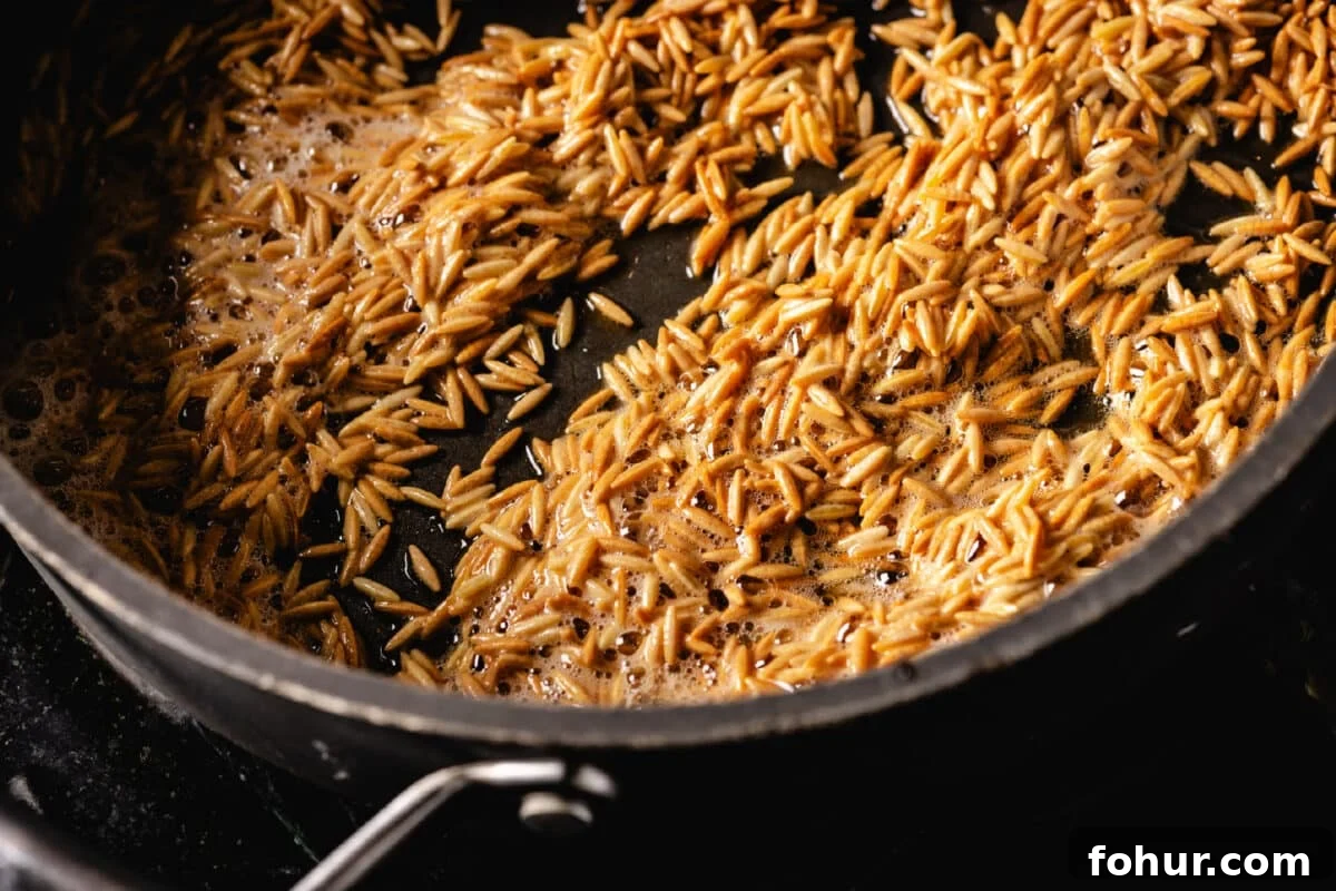 Savory Garlic Rice Pilaf with Lemon and Herbs 5 A close up shot of orzo toasting in oil in a large pan.