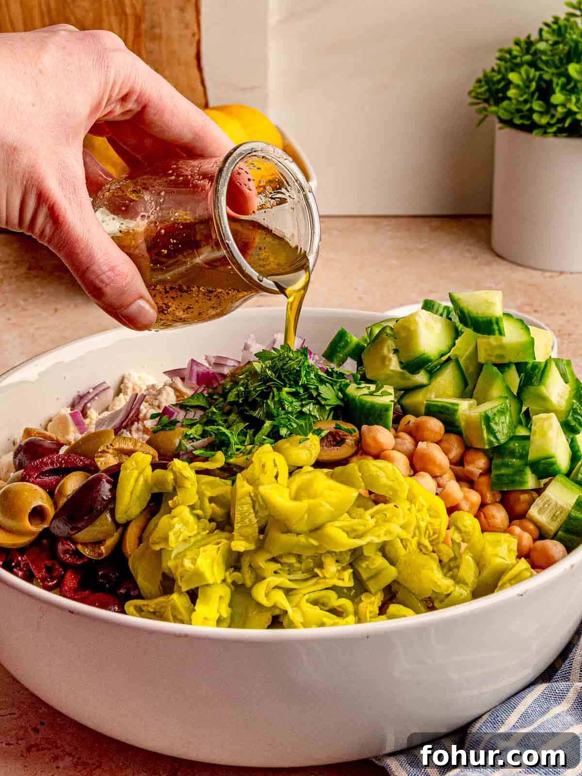 Zesty Lemon Orzo Salad with Feta and Herbs 5 Dressing being poured onto a salad.