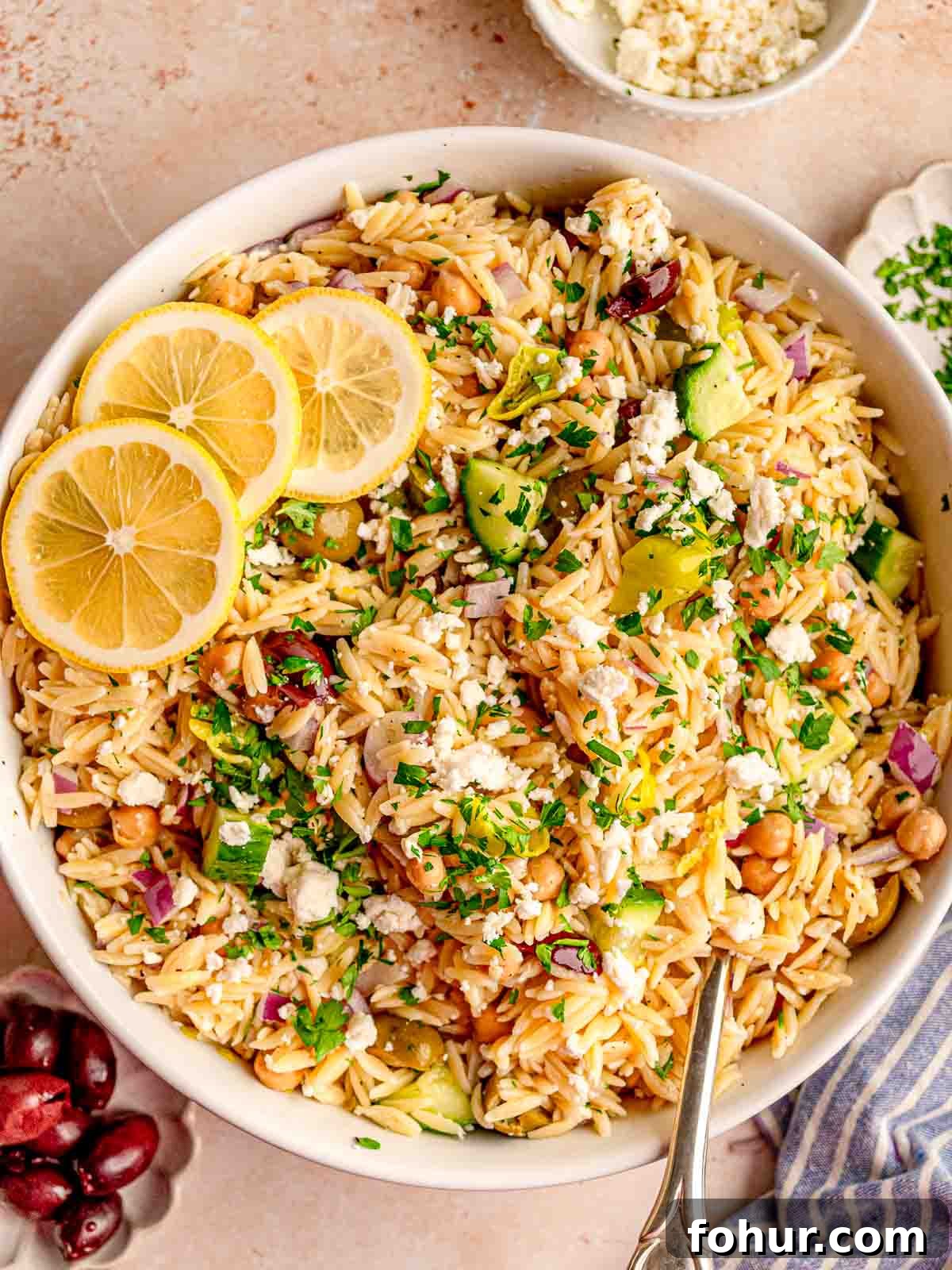 Zesty Lemon Orzo Salad with Feta and Herbs 6 Orzo in a bowl with cucumber, olives and chickpeas.