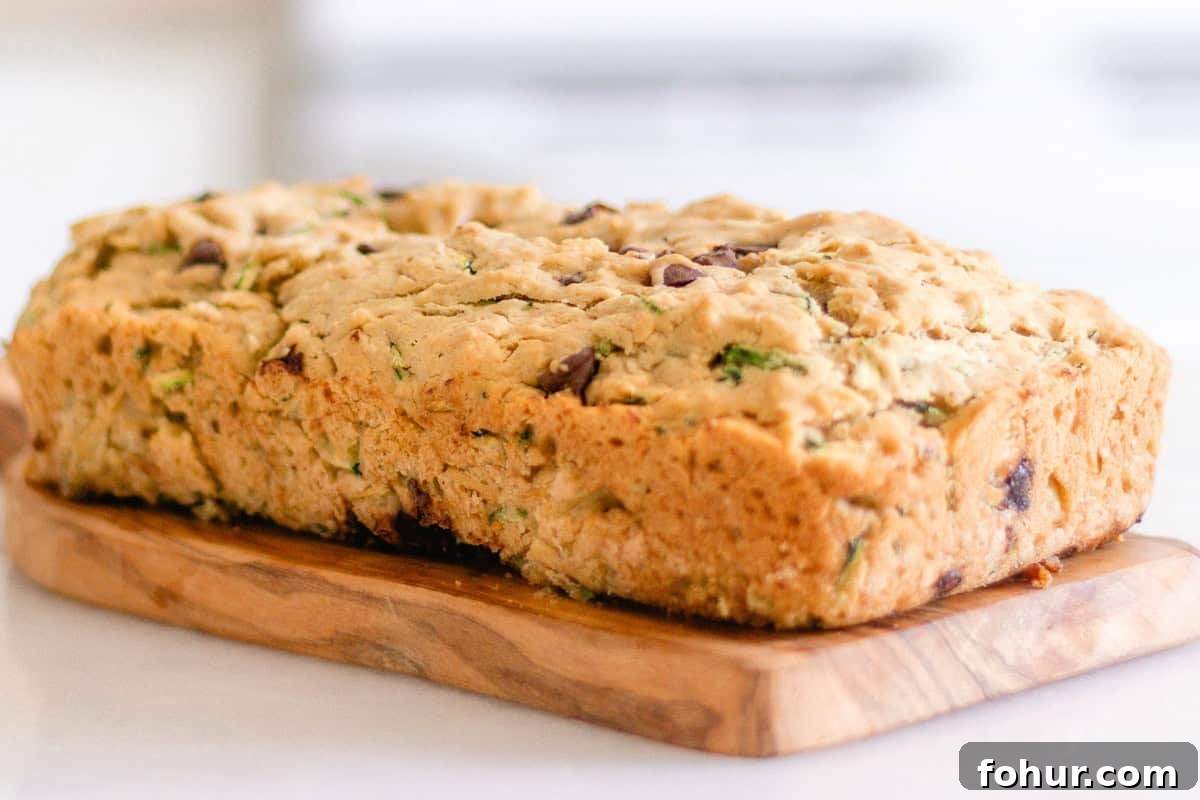 Moist Gluten-Free Zucchini Bread Recipe 3 A loaf of gluten-free zucchini bread on a wooden board.