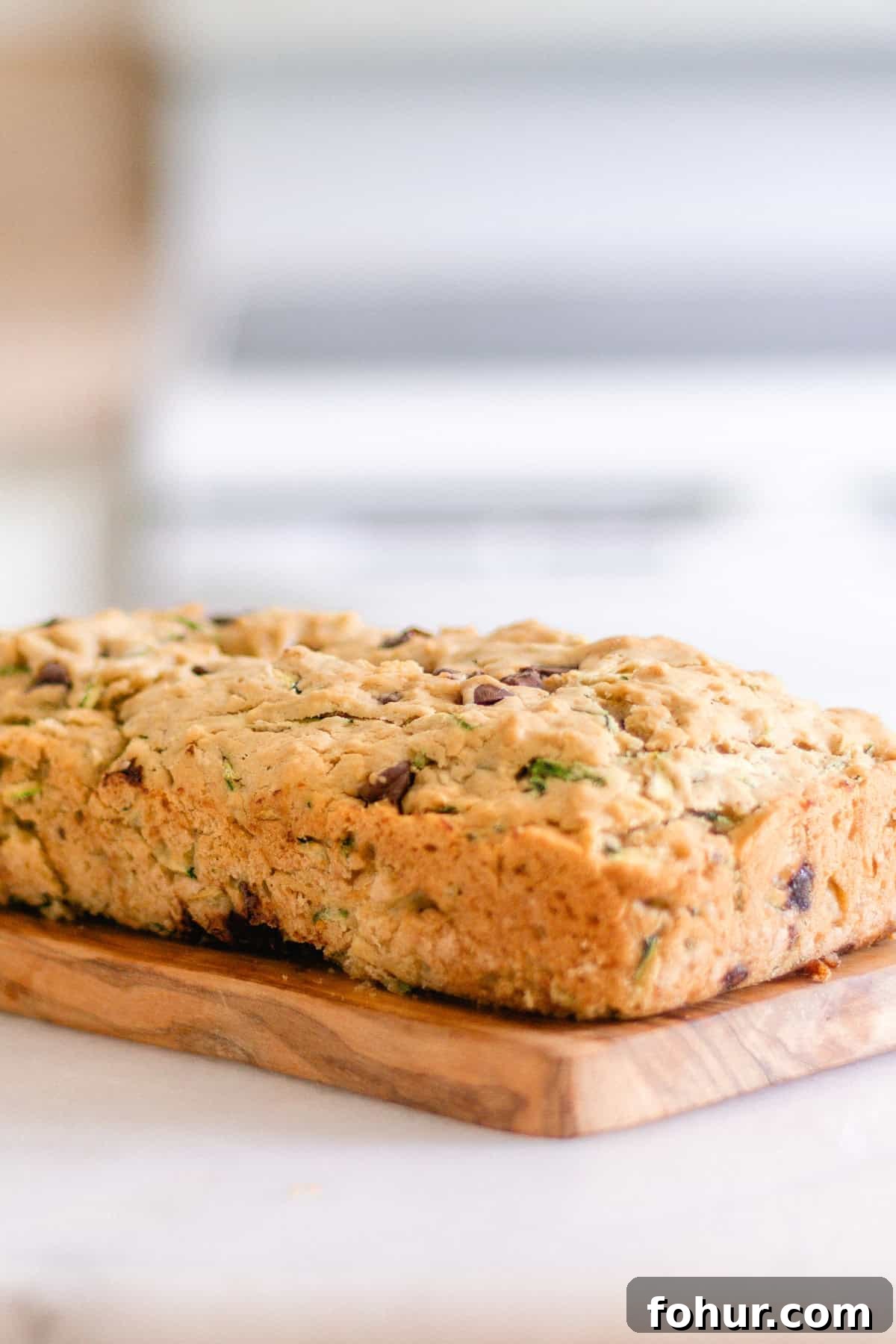 Moist Gluten-Free Zucchini Bread Recipe 9 A loaf of gluten-free zucchini bread on a wooden board.
