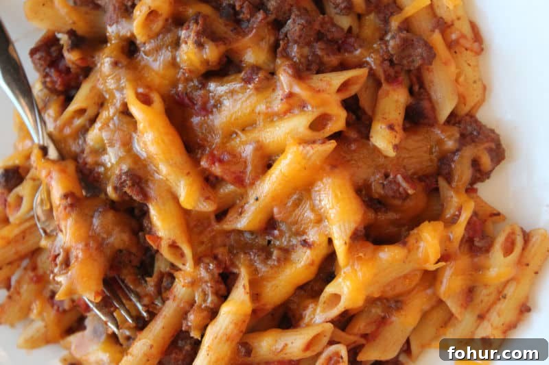 Slow Cooker Cheesy Beef Pasta Casserole Recipe (Video) 4 cheesy pasta beef casserole on a white plate with fork