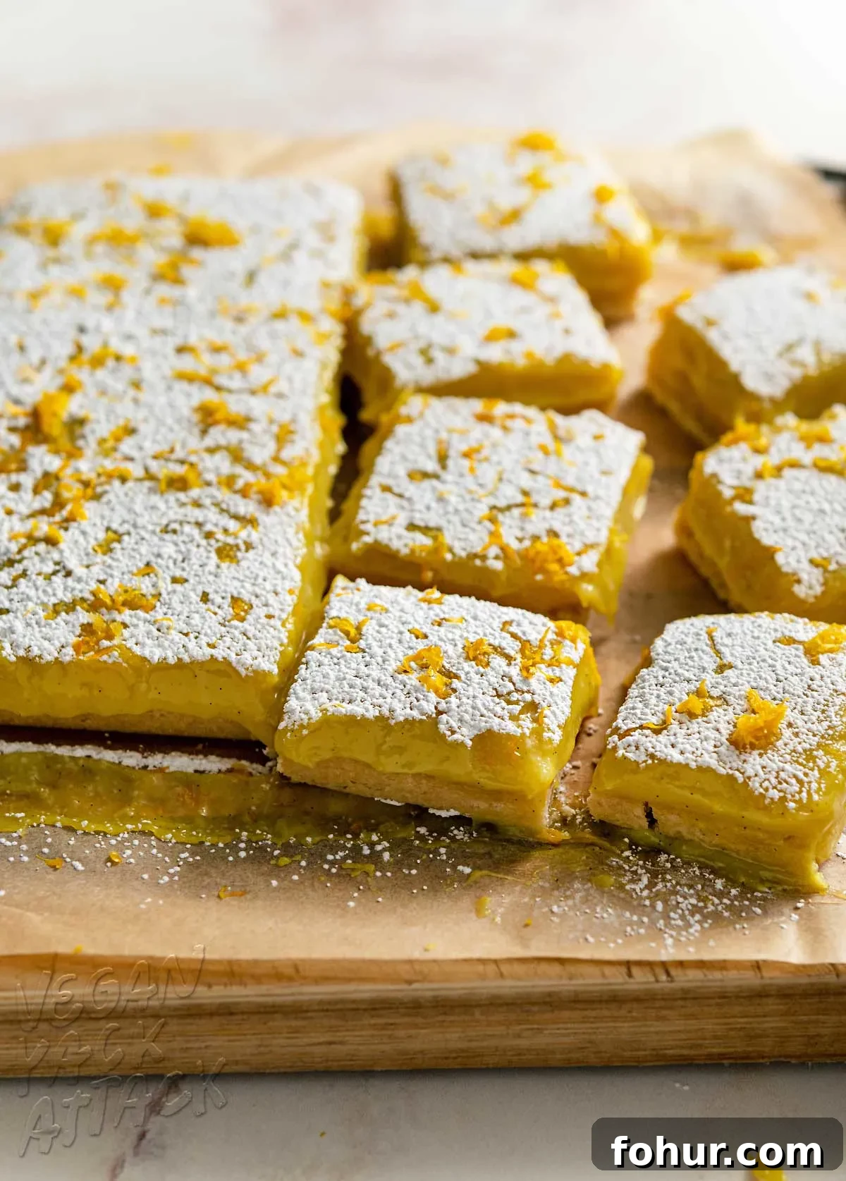 Fresh batch of vegan lemon bars being cut on a cutting board
