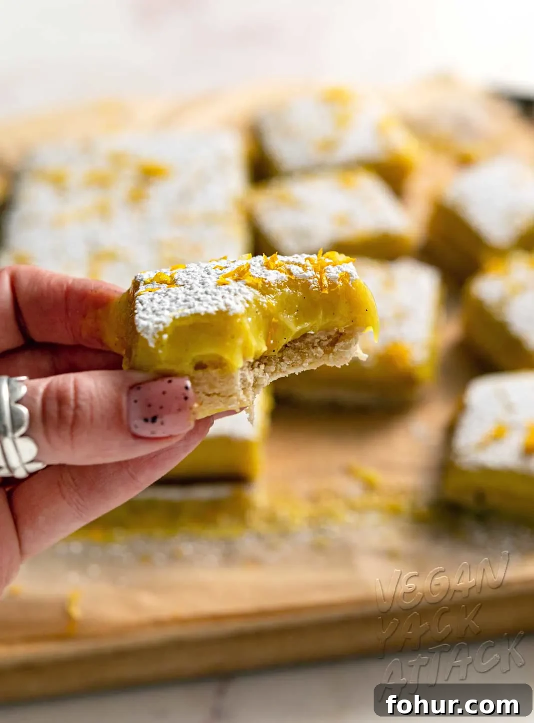 Hand holding lemon bar that has a bit taken out of it