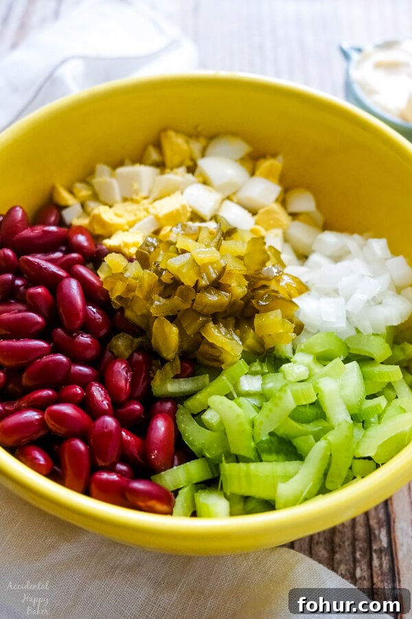 A yellow bowl full of the ingredients to make the salad before the dressing has been added.