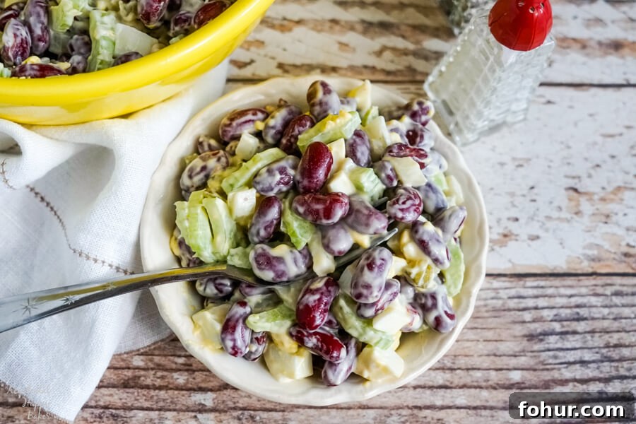 A small white bowl of old fashioned kidney bean salad next to salt and pepper shakers.