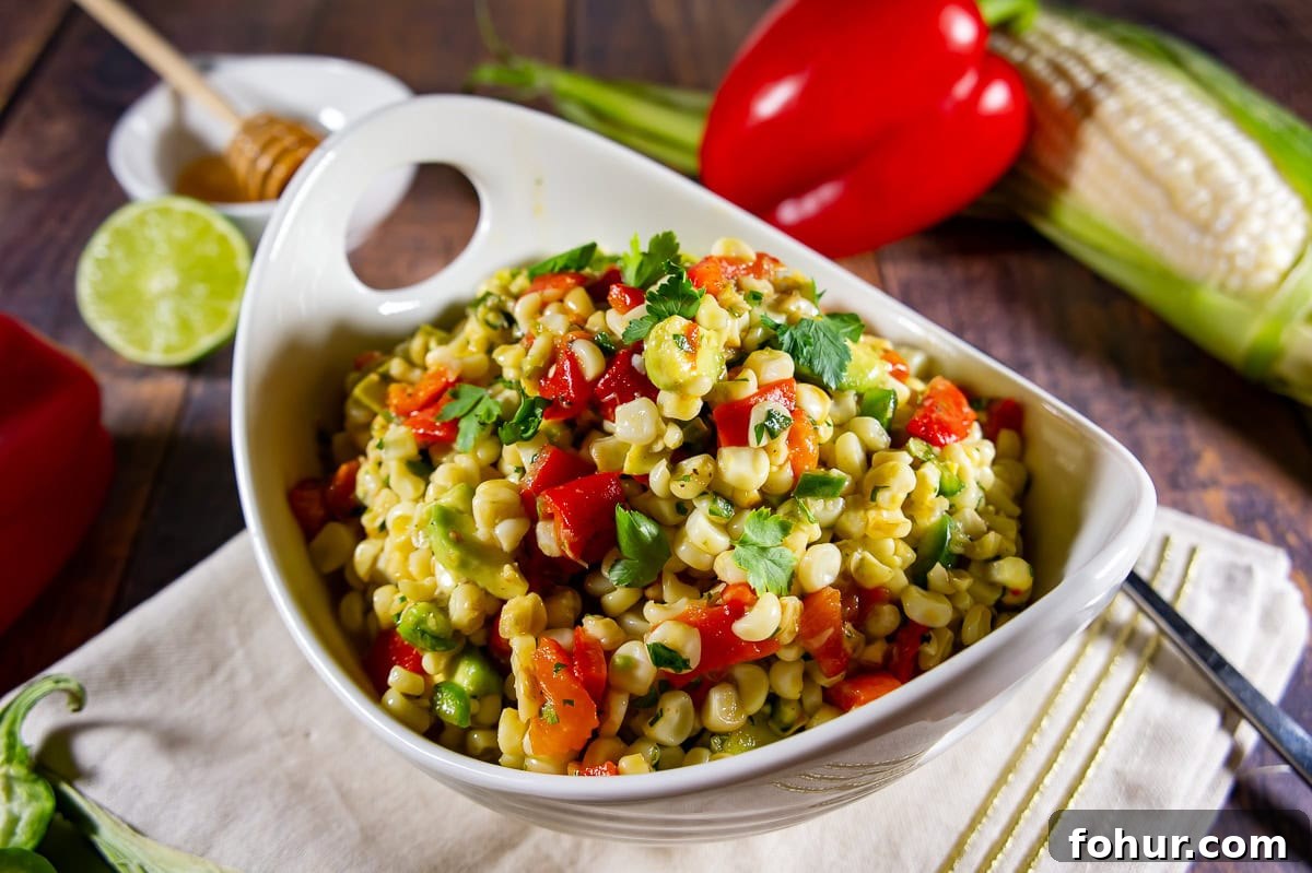 a bowl of corn and avocado salad with roasted red peppers